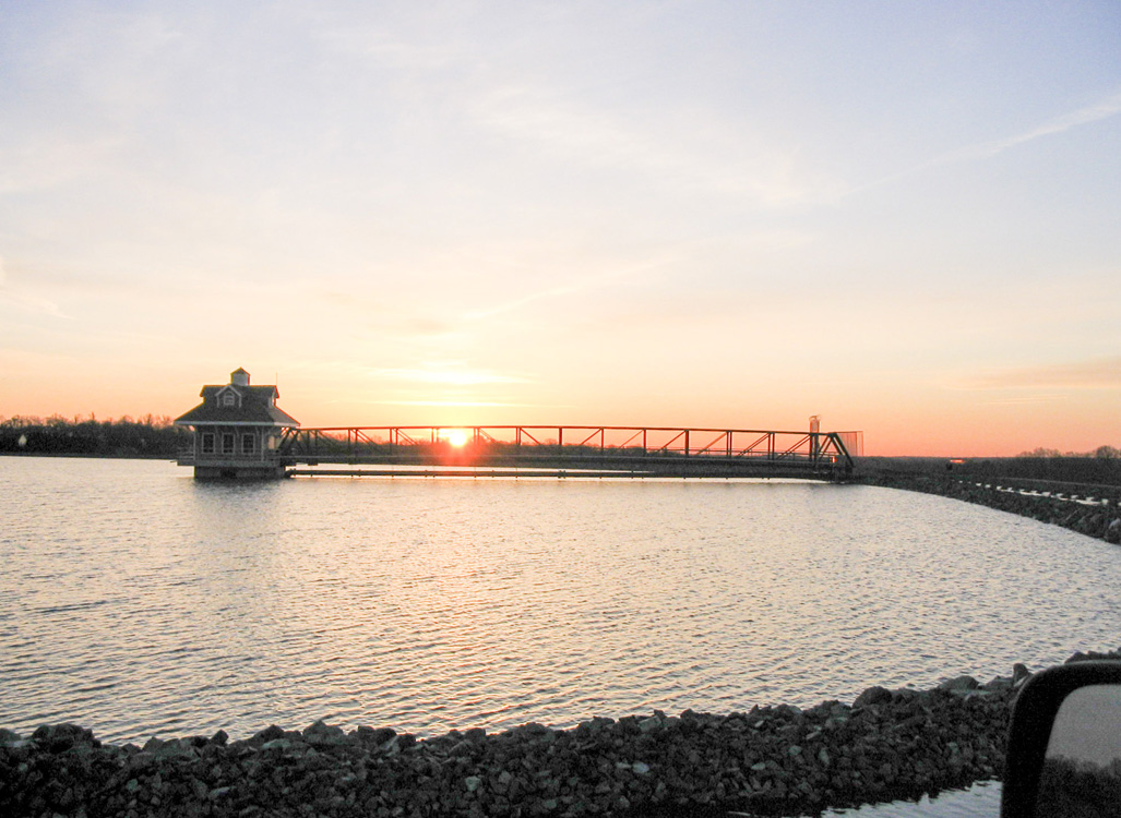 Sunset behind the bridge and building structure at Newark Reservoir in Newark, Delaware