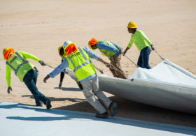Workers installing geosynthetic clay liner