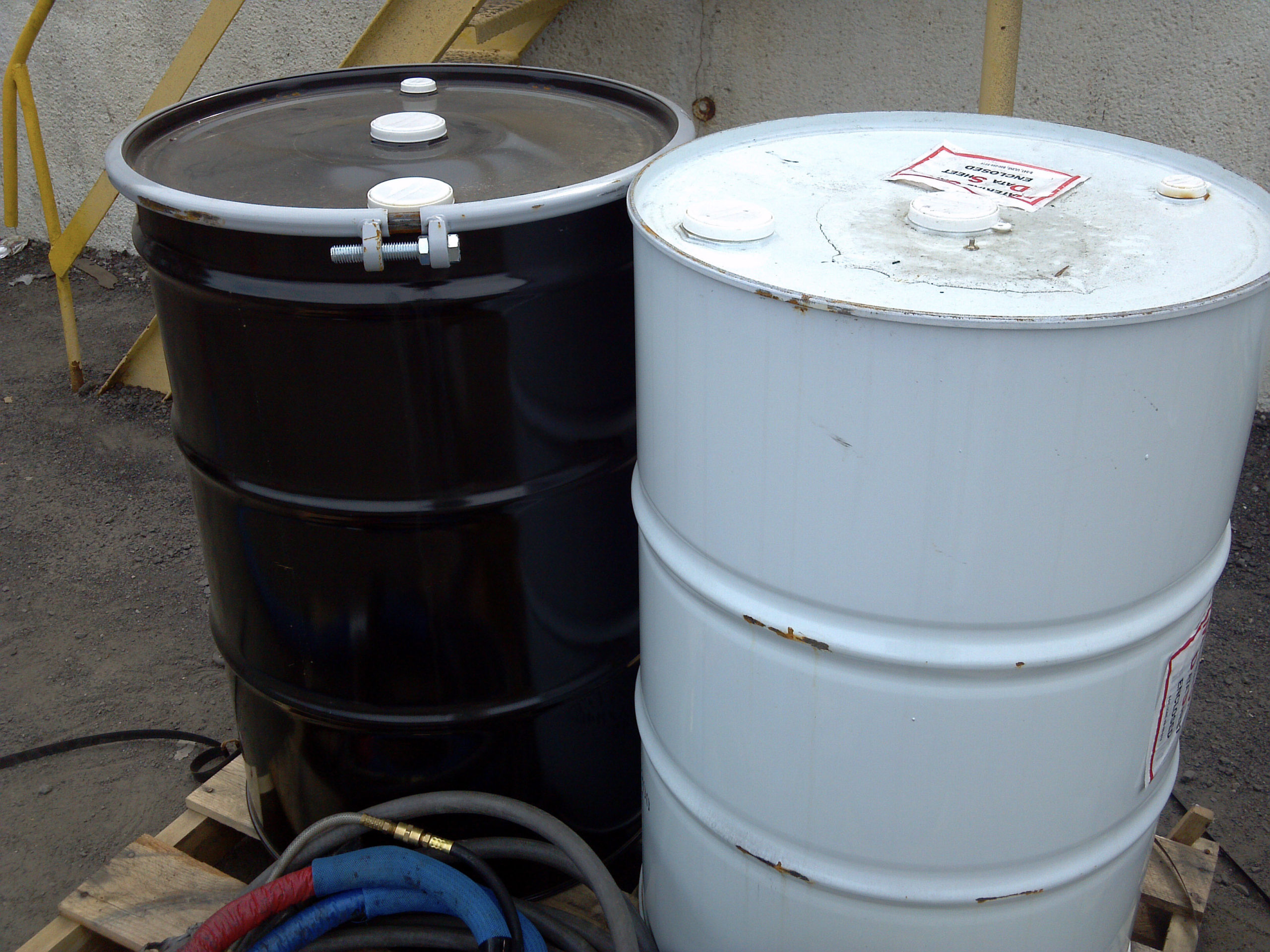Barrels containing resin and isocyanate components used for installation of polyurea spray liner material